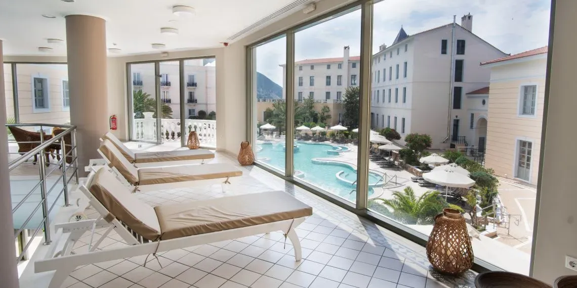 lounge area with lounge chairs overlooking pool and white building