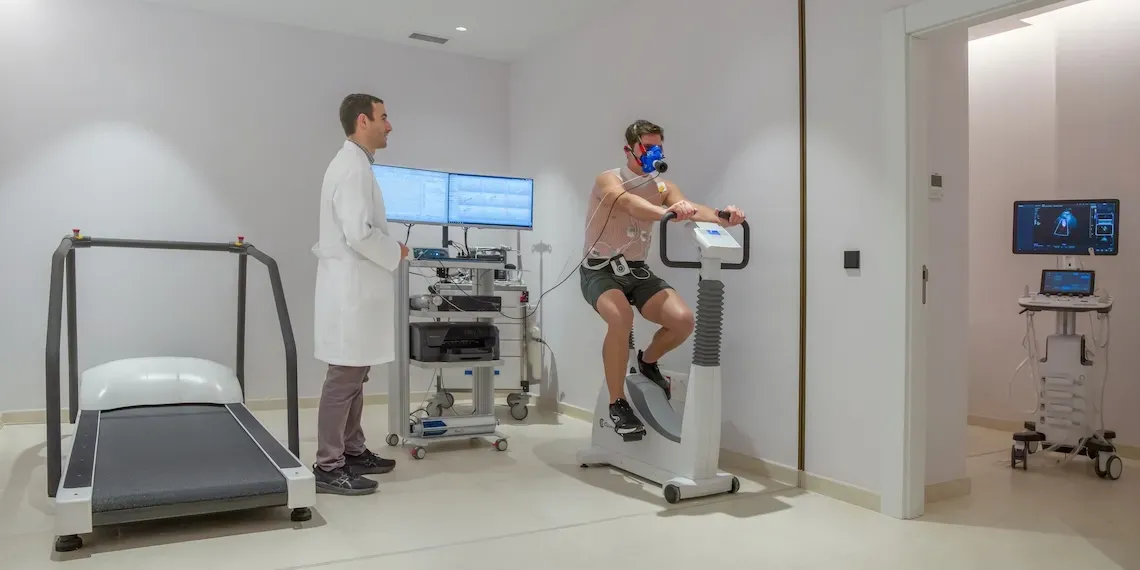 cardiology unit with man on a bike machine with sensors on his body and an oxygen mask with a doctor supervising