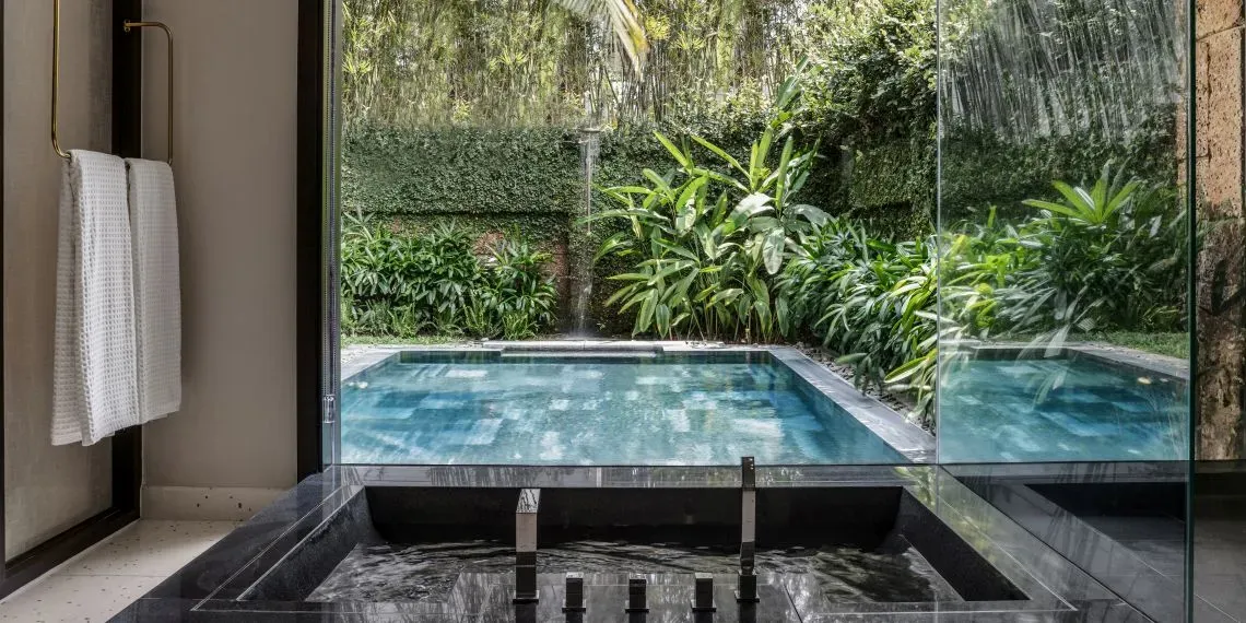 bath with view outside to pool and tropical garden