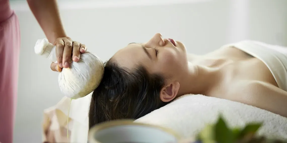 woman getting herbal stamp treatment on her head