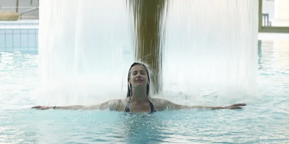 lady in a pool underneath a water stream