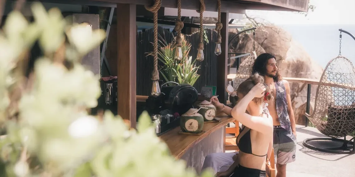 two people drinking from coconut at the bar