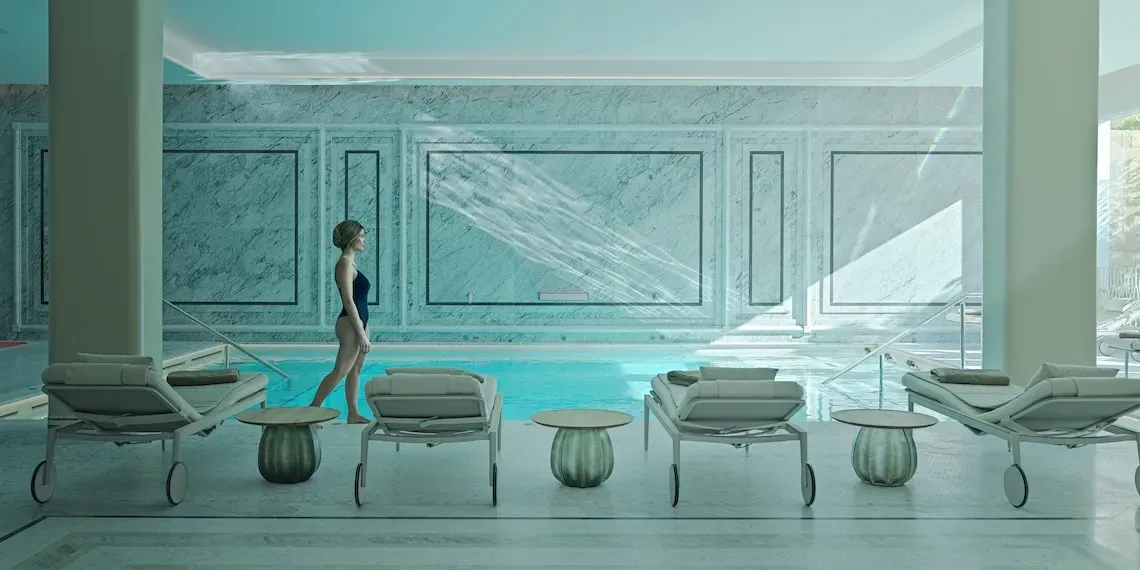 woman walking in a white spa in front of a pool and lounge beds