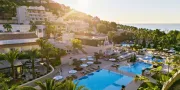 hotel view with pools and mountains and the sea in the distance