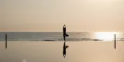 woman doing yoga on the beach at the pool