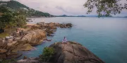 man in lotus yoga pose on a rock with sea view