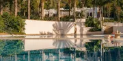 woman outside in front of an outdoor pool and palm trees