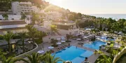 hotel view with pools and mountains and the sea in the distance