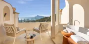 balcony with two chairs and a bath tub with views of the sea and mountains