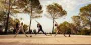 three woman in yoga pose on outdoor deck in front of trees